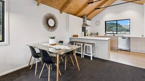 Una cocina moderna con techo de madera, un comedor con mesa de vidrio y vistas al exterior.