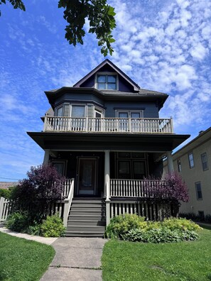 A two-story house with a balcony, a front porch, and a driveway.