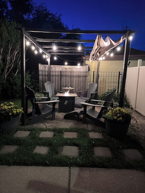 A patio with outdoor furniture, a fire pit, and string lights.