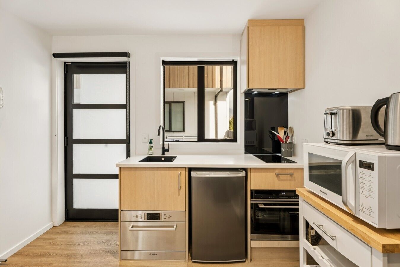 A compact kitchen with a dishwasher, oven, microwave, and a coffee maker on the counter.