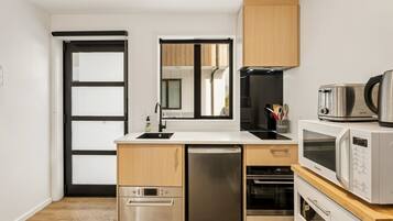 A compact kitchen with a dishwasher, oven, microwave, and a coffee maker on the counter.