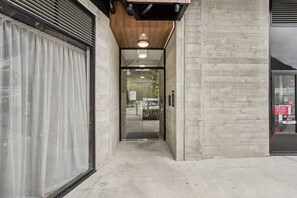 Ein Gebäudeeingang mit Betonfassade, Glastür und erkennbarem Feuerwehranschlussschild.