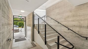 A modern interior with a staircase, a door leading outside, and a visible outdoor area.
