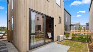 Moderni rakennus, jossa on puinen julkisivu, suuret liukuvat lasiovet ja pieni puutarha-alue.