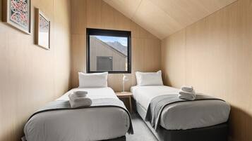 A hotel room with two beds, a window with a mountain view, and framed artwork on the wall.