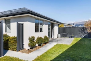 A modern house with a garage, a patio, and a well-maintained lawn. - Best for Mates! Double Ensuite Home! (Cromwell)