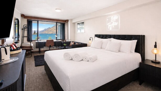Une chambre d’hôtel avec un grand lit, un bureau, une chaise, une télévision et une vue sur la mer.