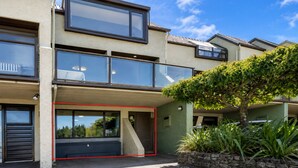 Un immeuble résidentiel moderne à plusieurs étages, doté de grandes fenêtres, d’un balcon et d’un garage.