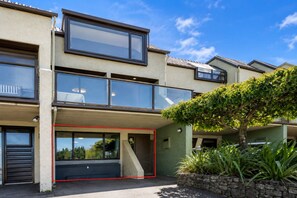 En moderne boligbygning i to etager med store vinduer, en balkon og en garage.