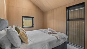 Un dormitorio con cama, almohadas, ventana y puerta corredera.