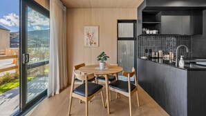 Una cocina moderna con armarios oscuros, una mesa redonda con sillas y vistas amplias por ventanas grandes.