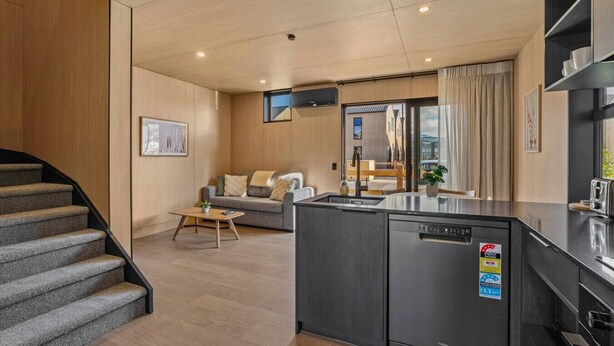 Un apartamento moderno con cocina, sala de estar y una escalera.