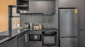 Una cocina moderna con horno empotrado, microondas y refrigerador de acero inoxidable.