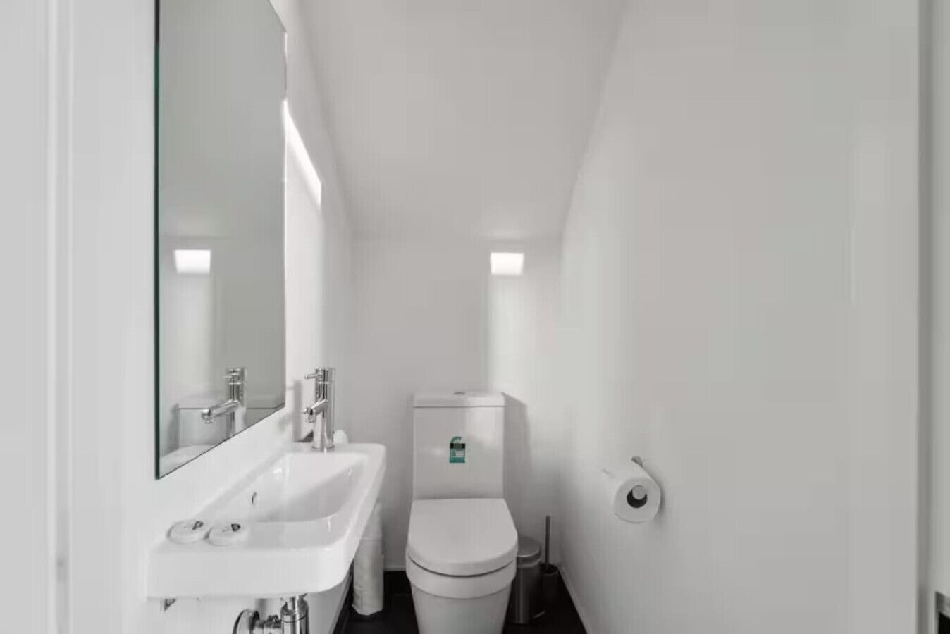 Une petite salle de bain blanche, équipée d’un lavabo, de toilettes et d’un miroir.