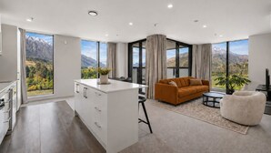 Una sala de estar moderna con un sofá, una mesa de centro y vistas a montañas a través de amplios ventanales.