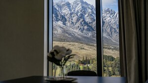 Una habitación con un ventanal que ofrece vistas a montañas nevadas y un valle.