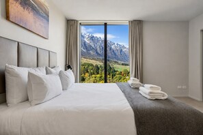 Et hotelværelse med en stor seng, udsigt til bjerge og et vindue med gardiner.