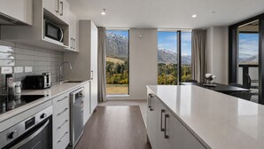 Una cocina moderna con una isla grande, microondas, cafetera y vistas a montañas a través de las ventanas.