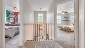 A hallway with a staircase leading to a bedroom with a bed and a ceiling fan. - Comfy 4-Bedroom House in Castle Rock with Priv. Fenced-in Backyard/Dog Friendly. (Castle Rock)