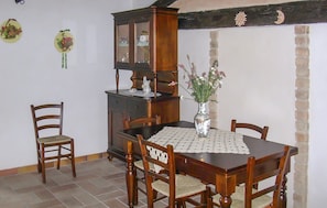 Ein Essbereich mit Holztisch, Stühlen, einem Schrank und einer Vase mit Blumen.