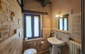 Ein Badezimmer mit Toilette, Waschbecken und einem Fenster mit Vorhängen.