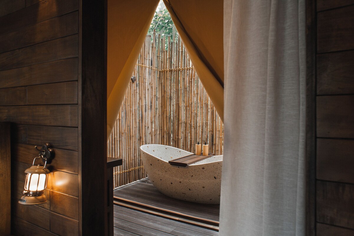 Un área de spa con una bañera independiente, paredes de madera y un farol.