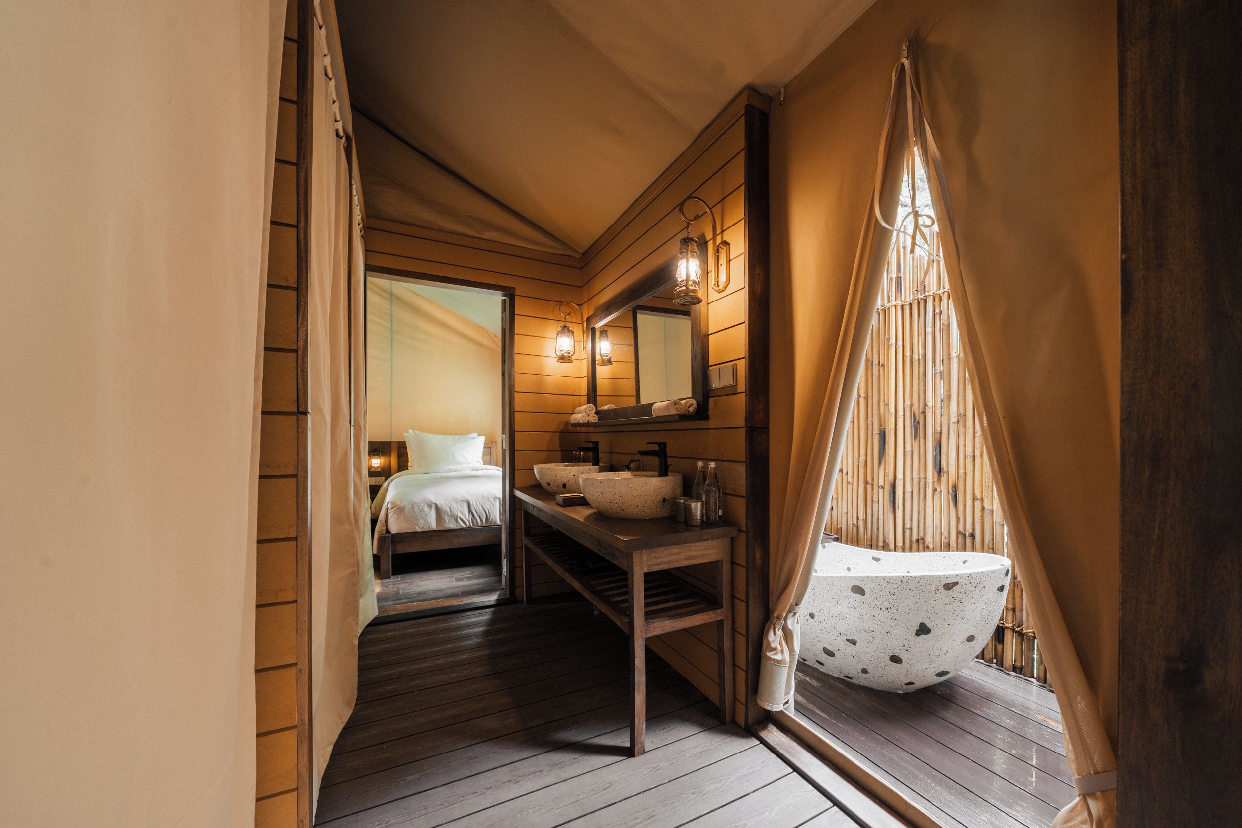 Un estrecho pasillo de madera que conduce a un dormitorio con una cama, un banco de madera y una pileta grande.