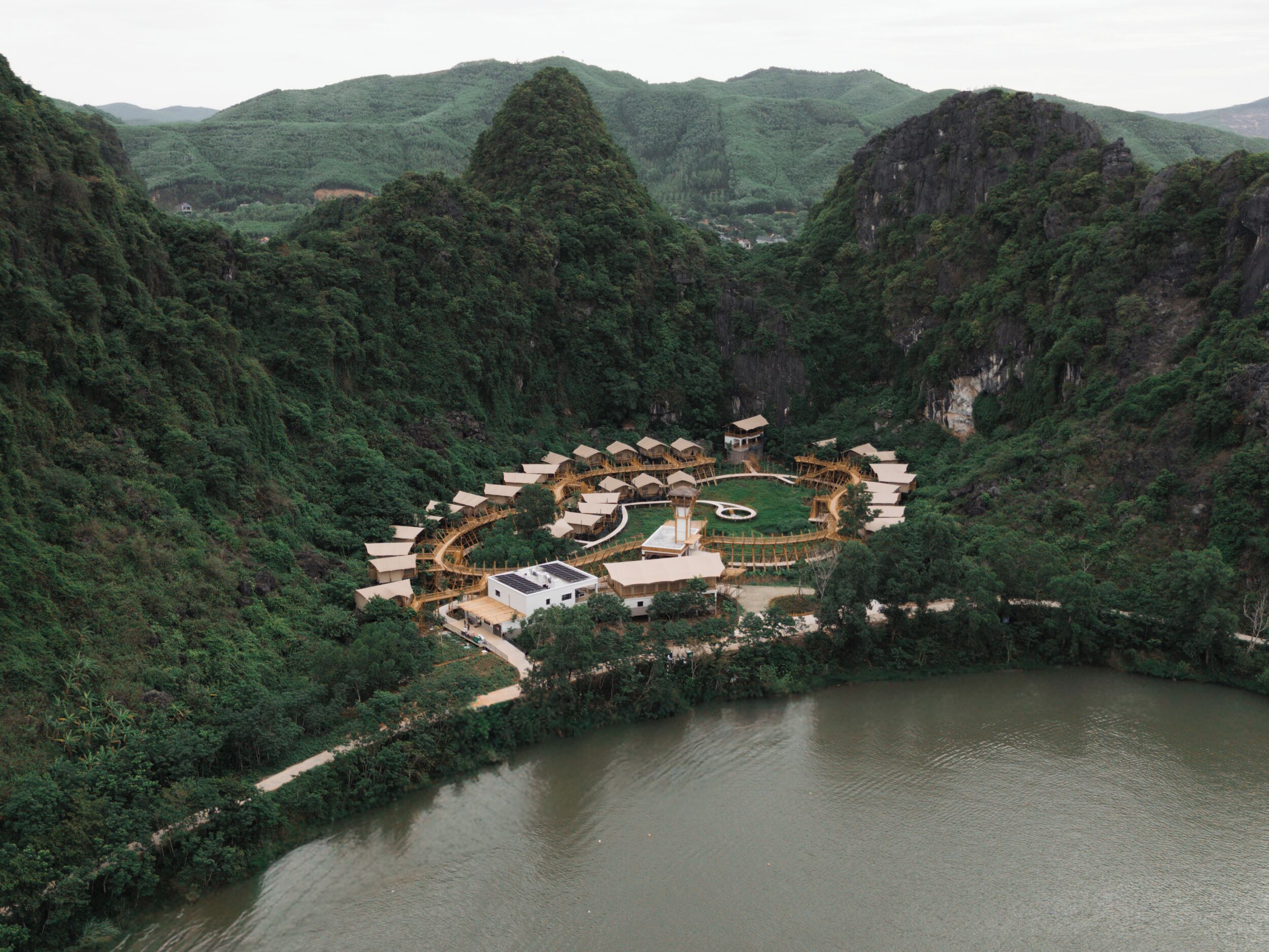 A resort with a circular layout of buildings, a central courtyard, and a surrounding natural landscape.