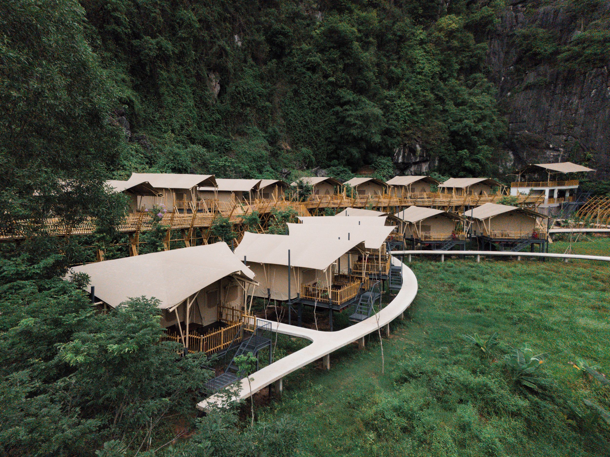 A series of elevated wooden structures with attached walkways, surrounded by dense forest.