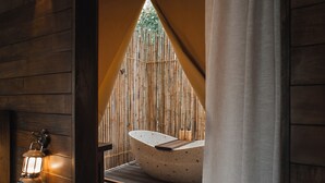 A spa area with a freestanding bathtub, wooden walls, and a lantern.