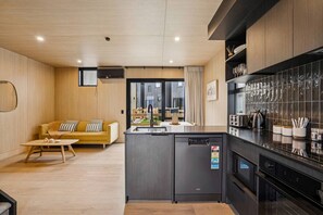 Een moderne keuken met een inbouwkoelkast, een eethoek met een tafel en stoelen, en een woonkamer met een bank en salontafel.