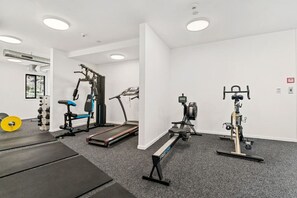 Un gimnasio con máquinas de cardio, pesas libres y una cinta de correr.