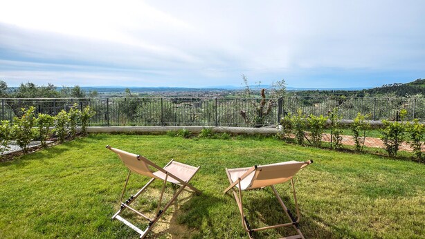 A grassy outdoor area with two folding chairs and a view of a distant landscape. - Il Borgo di Badia-La Camelia (Buti)