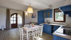 A kitchen with blue cabinets, a white table, and chairs. - Il Borgo di Badia-La Camelia (Buti)
