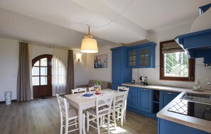 Eine Küche mit blauen Schränken, einem weißen Tisch und Stühlen.