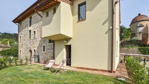 A two-story building with a stone facade, a flat roof, and a dome structure in the background. - Il Borgo di Badia-La Camelia (Buti)
