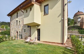 Ein zweistöckiges Gebäude mit einer Stein-Fassade, einem flachen Dach und einer Kuppelstruktur im Hintergrund.