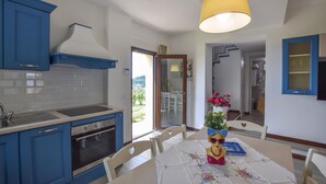 A kitchen with blue cabinets, a stove, and a sink. There's a dining table with chairs and a decorative item on it. - Il Borgo di Badia-La Camelia (Buti)