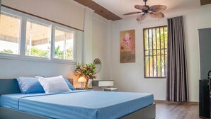 A bedroom with a bed, a ceiling fan, a window with curtains, a painting, and a nightstand with a lamp. - Favos Bich Dong (Ninh Binh)