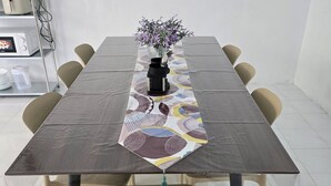 A long dining table with a patterned runner, clear chairs, and a vase with flowers. - SD Homestay 81 Play Together, Fun Forever (George Town)
