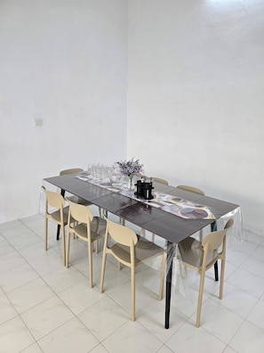 A dining table with chairs, a vase with flowers, and a black object on the table. - SD Homestay 81 Play Together, Fun Forever (George Town)
