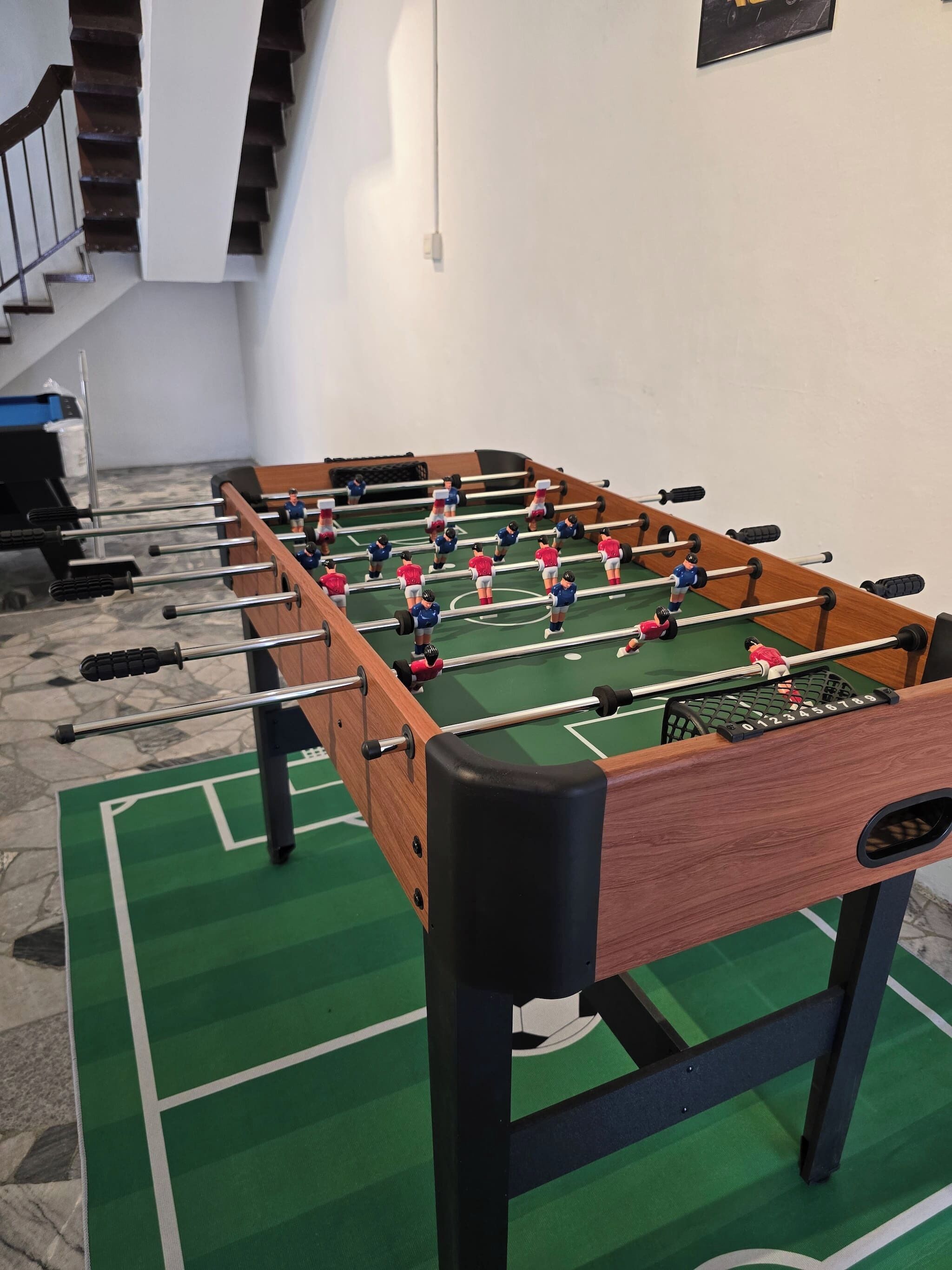 A foosball table with a green playing surface and black and red player figures.