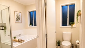 Un baño con bañera, inodoro y zona de ducha.