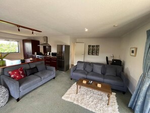 A living room with two sofas, a coffee table, and a kitchen area with appliances. - The Iron Gate - Best Value and Pet Friendly! (Cromwell)