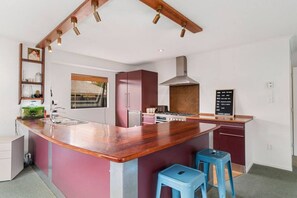 Een moderne keuken met een houten kookeiland, roestvrijstalen apparatuur en een krijtbordmenu.