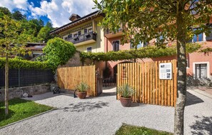 Ein Innenhof mit Kiesweg, Holztoren, Blumentöpfen und einem Gebäude mit Balkonen.