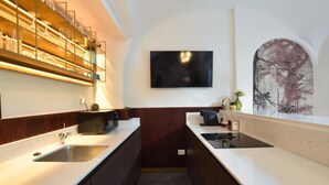 Een moderne keuken met een magnetron, gootsteen en een televisie aan de muur.