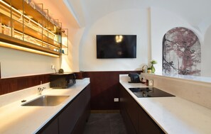 Eine moderne Küche mit Mikrowelle, Spüle und einem an der Wand befestigten Fernseher.