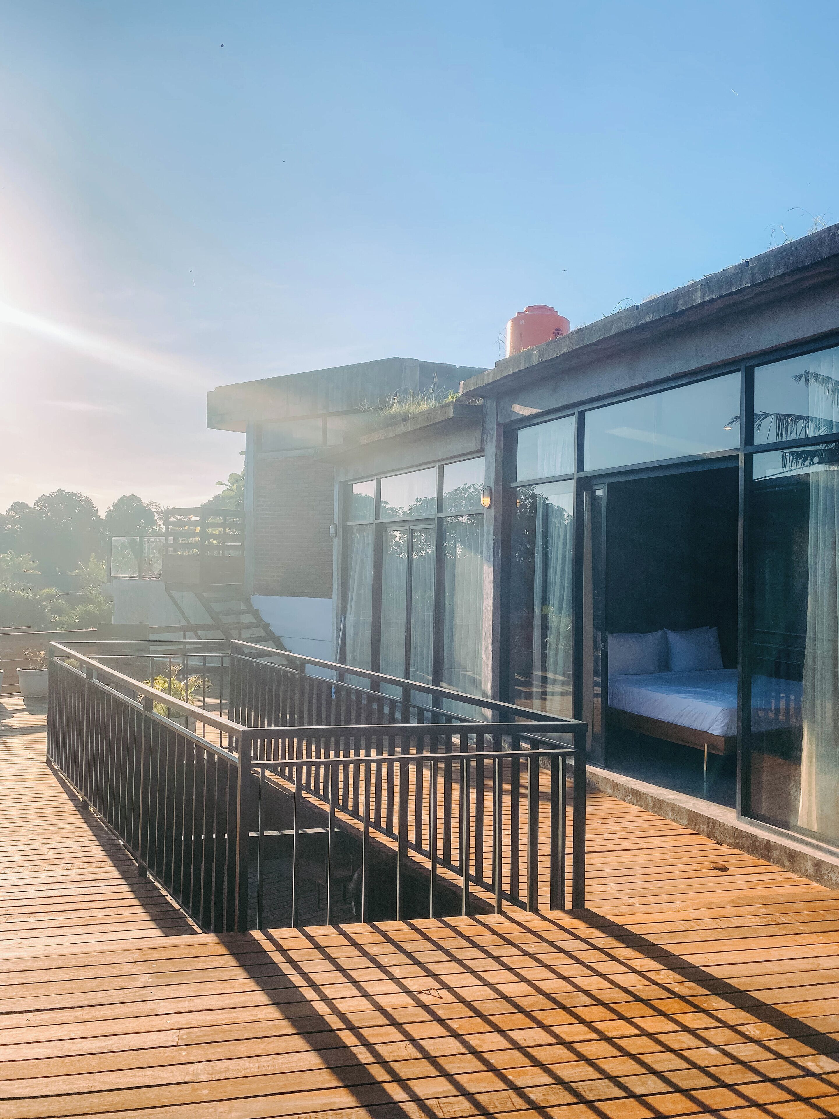Ein modernes Hotel mit einem gläsernen Raum, einer Holzterrasse und einem Metallgeländer.
