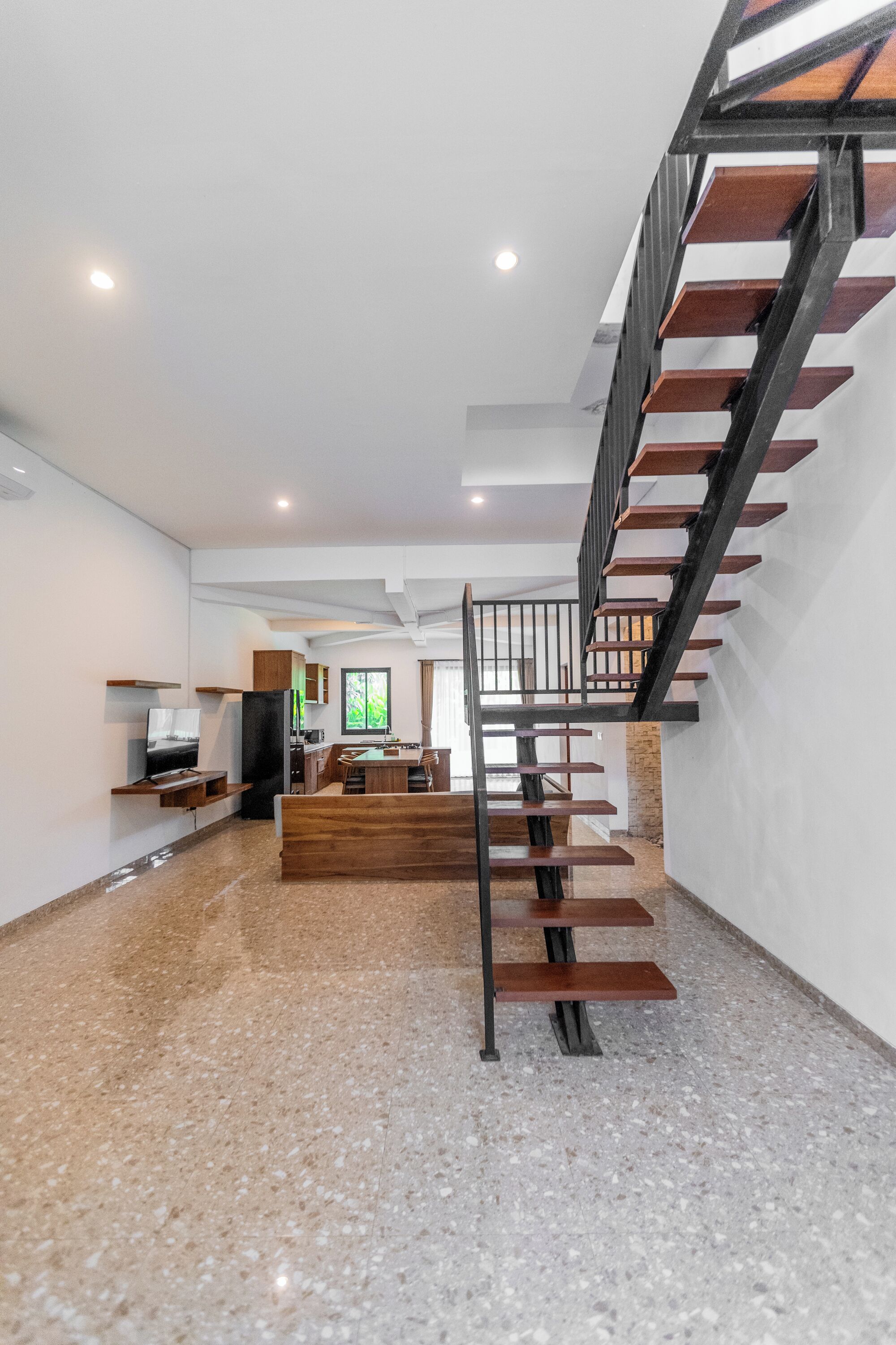 Un interior moderno con una escalera, una zona de cocina y un comedor.